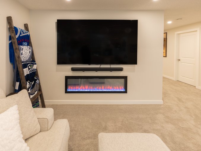 A wall-mounted television and soundbar sit above the recessed Napoleon electric fireplace on a simple neutral media wall.