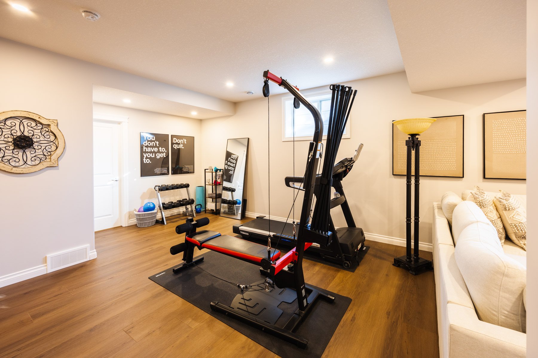 A functional home gym with cardio and strength equipment is integrated into this bright, family-first basement.