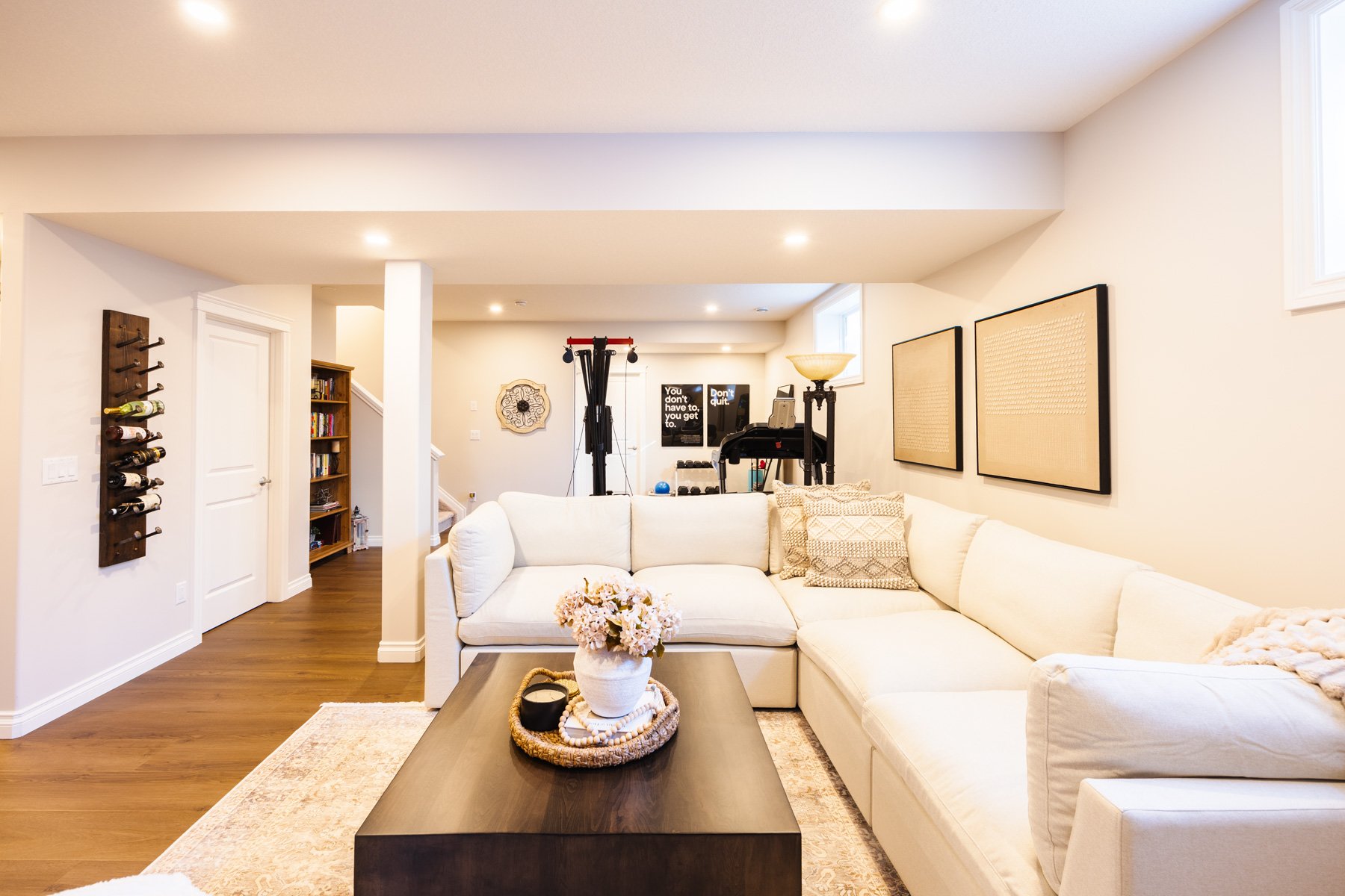 A seamless open-plan basement design connects the home bar, fitness area, and casual family seating.