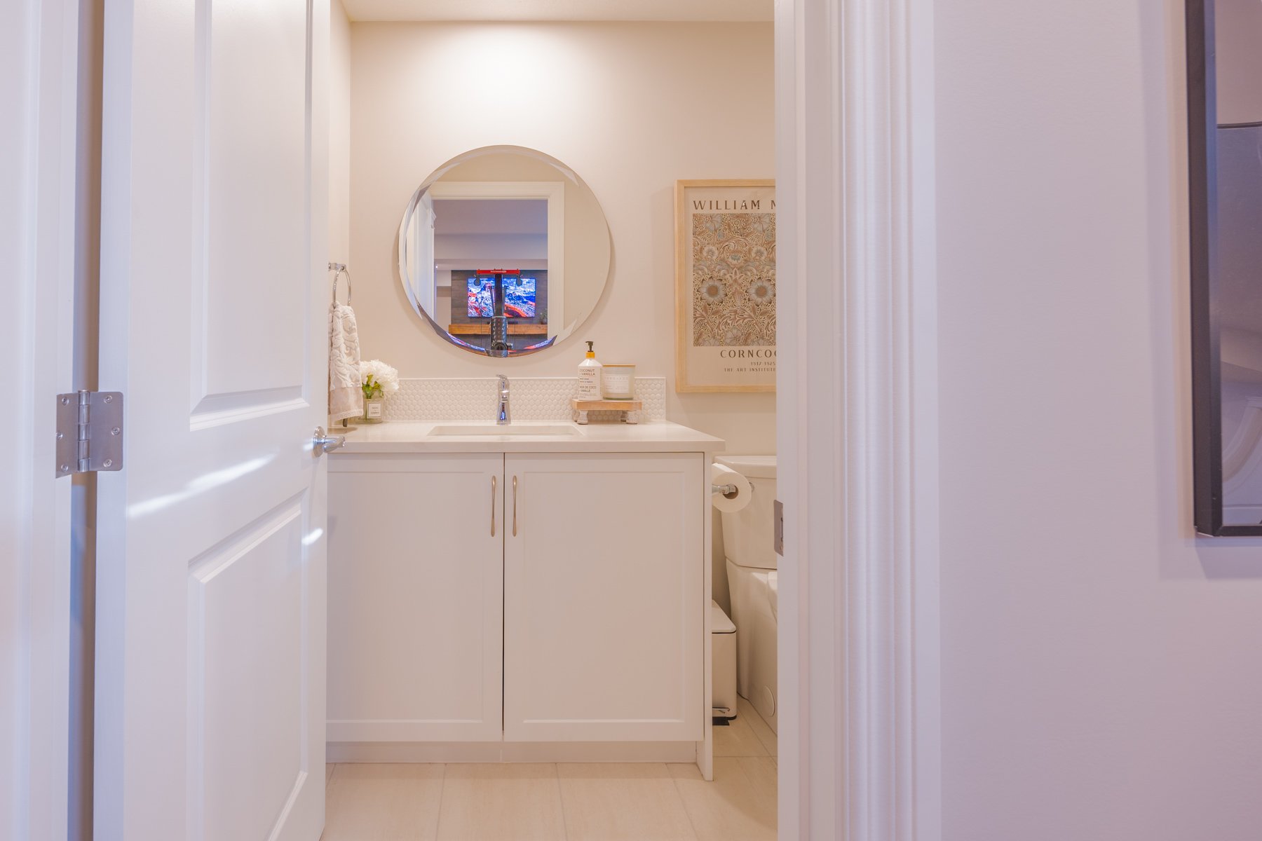 White shaker cabinetry, a round mirror, and a bright open connection to the custom basement gym.