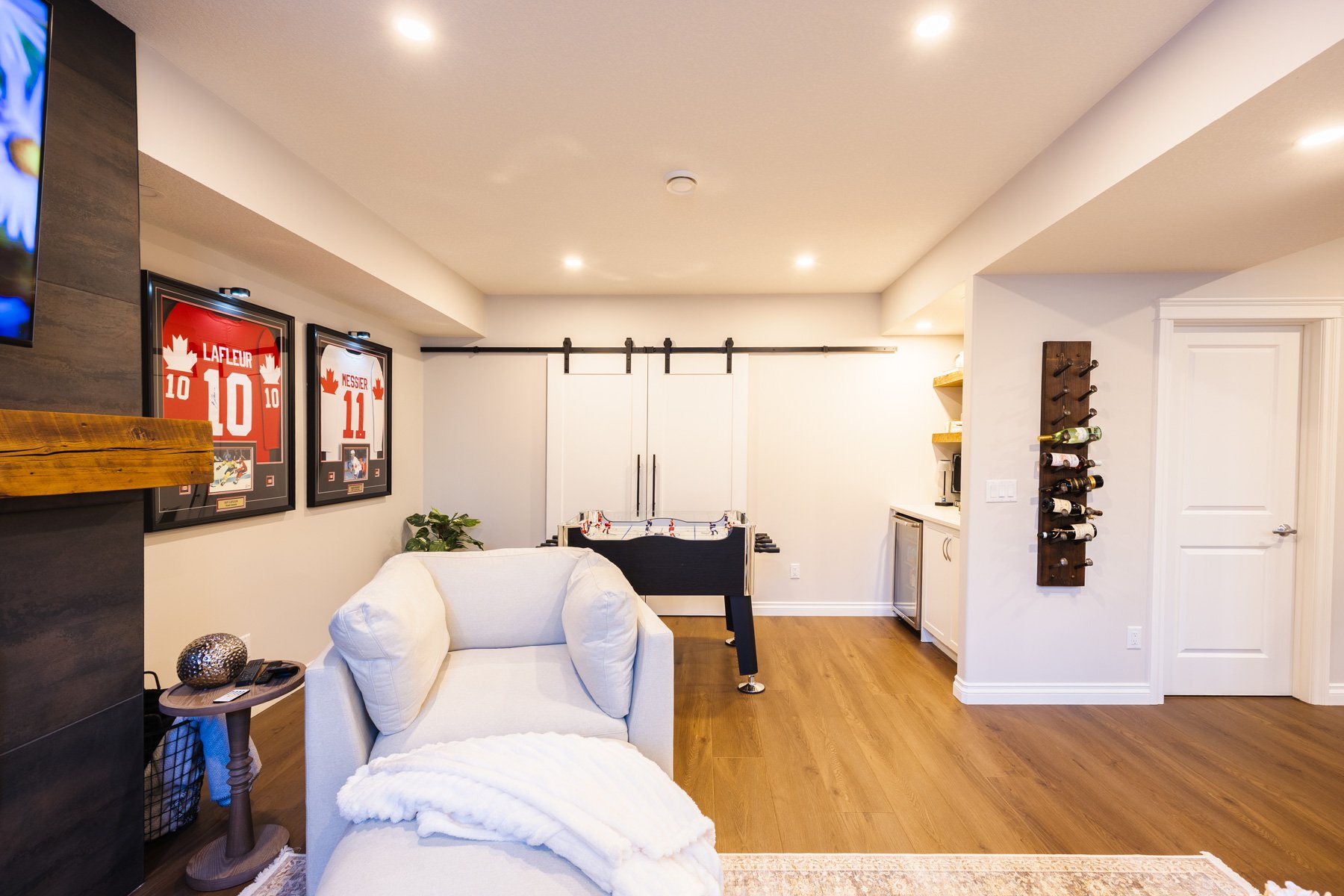 Comfortable white seating, warm flooring, and wall-mounted wine storage create an inviting entertaining area.