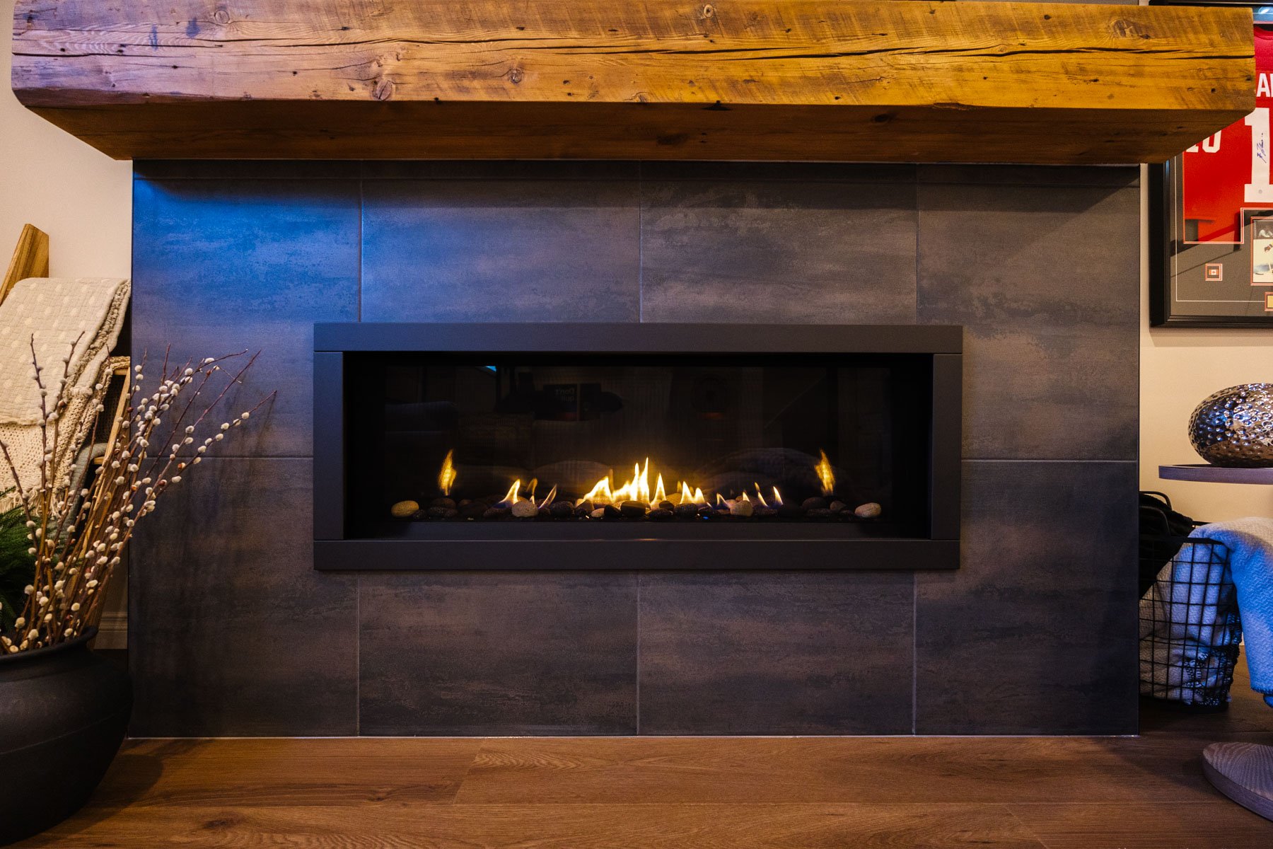 A sleek linear fireplace set within a dark tile feature wall brings warmth and style to the lower-level lounge.