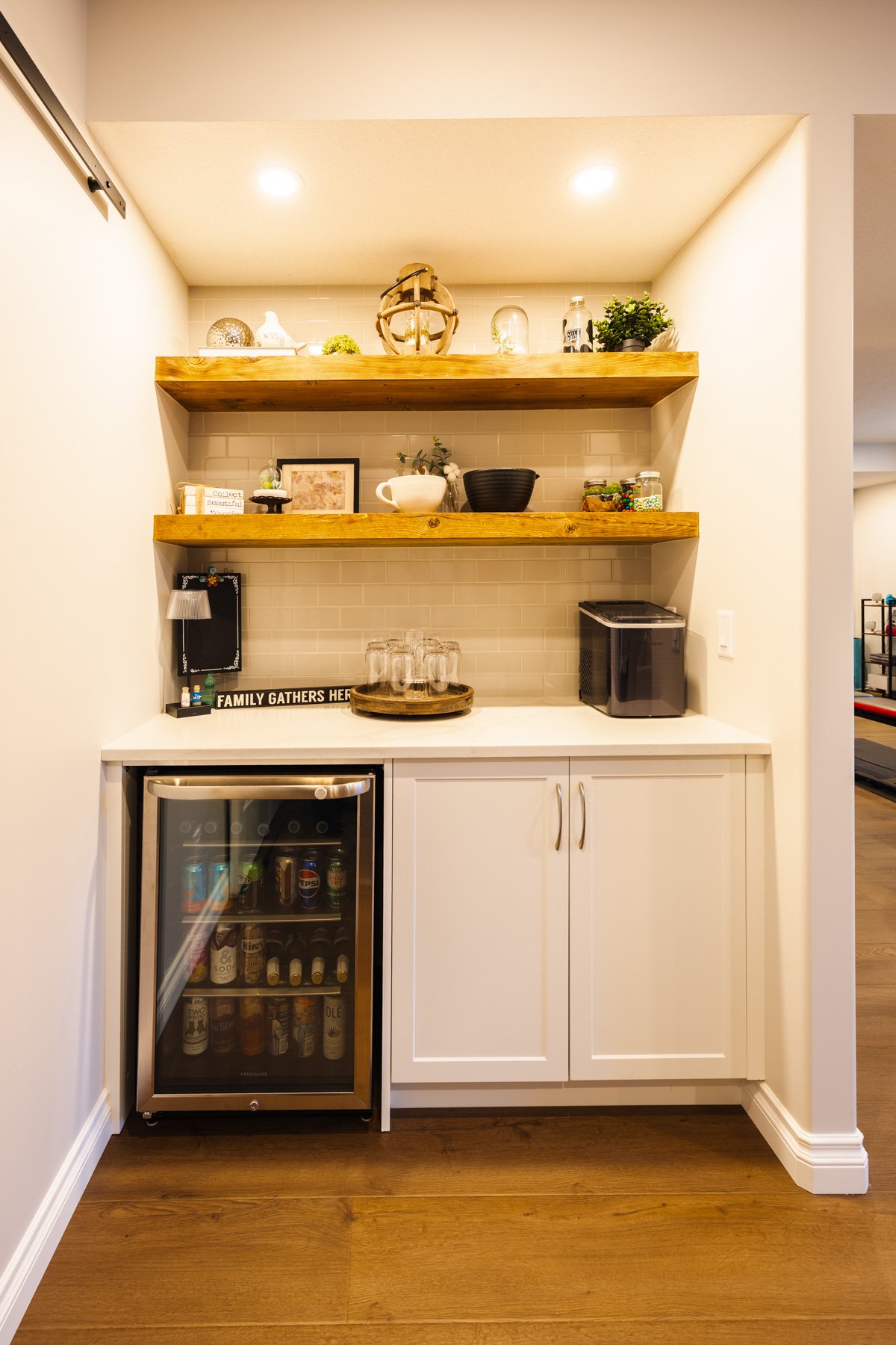 White shaker cabinetry, subway tile, wood shelves, and a glass-front beverage fridge make this a versatile home bar.