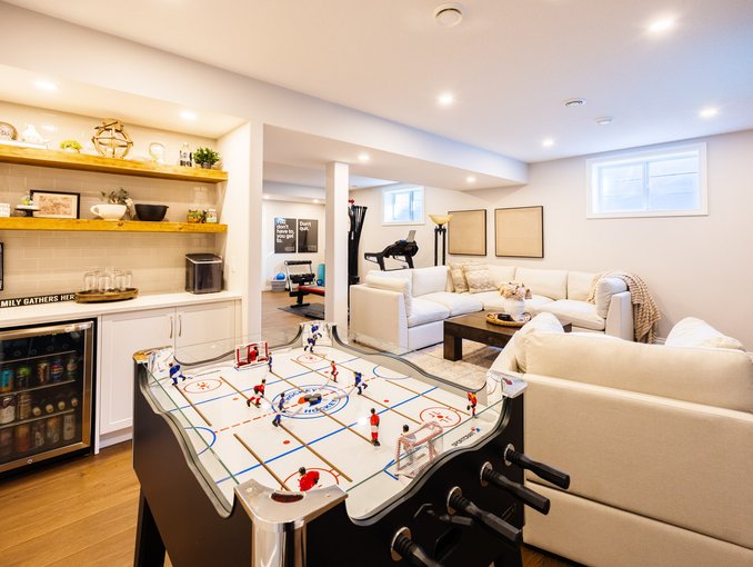A full view of the home bar, games table, lounge, and gym shows how this basement was designed for everyday family life.
