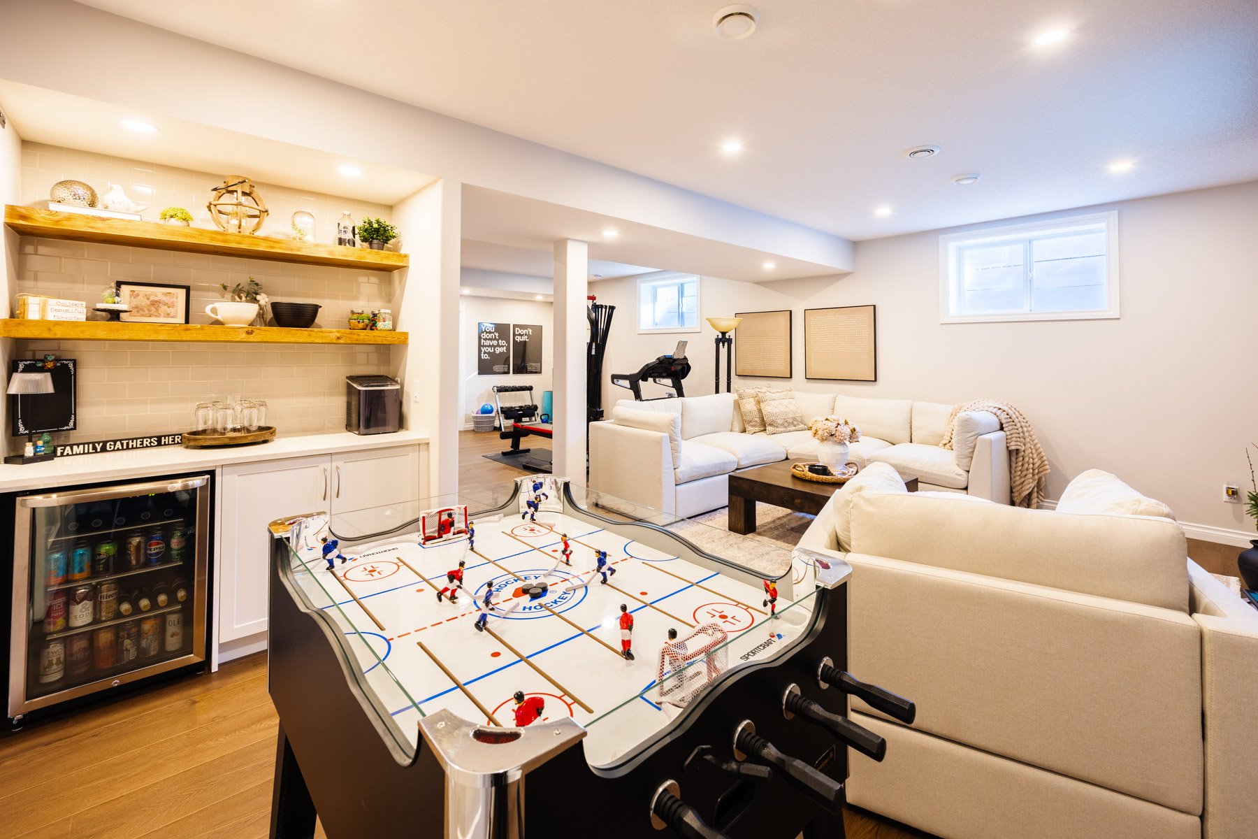A full view of the home bar, games table, lounge, and gym shows how this basement was designed for everyday family life.
