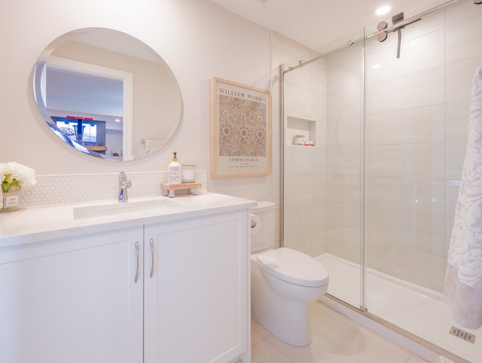 A welcoming basement bathroom finished with white cabinetry, brushed hardware, and a simple, refined palette.