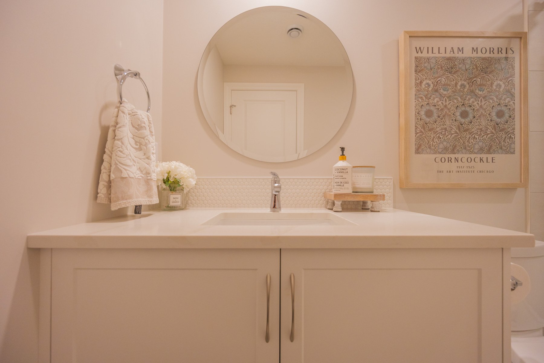 A clean, comfortable lower-level bathroom featuring a white vanity, toilet, tiled floor, and glass shower.