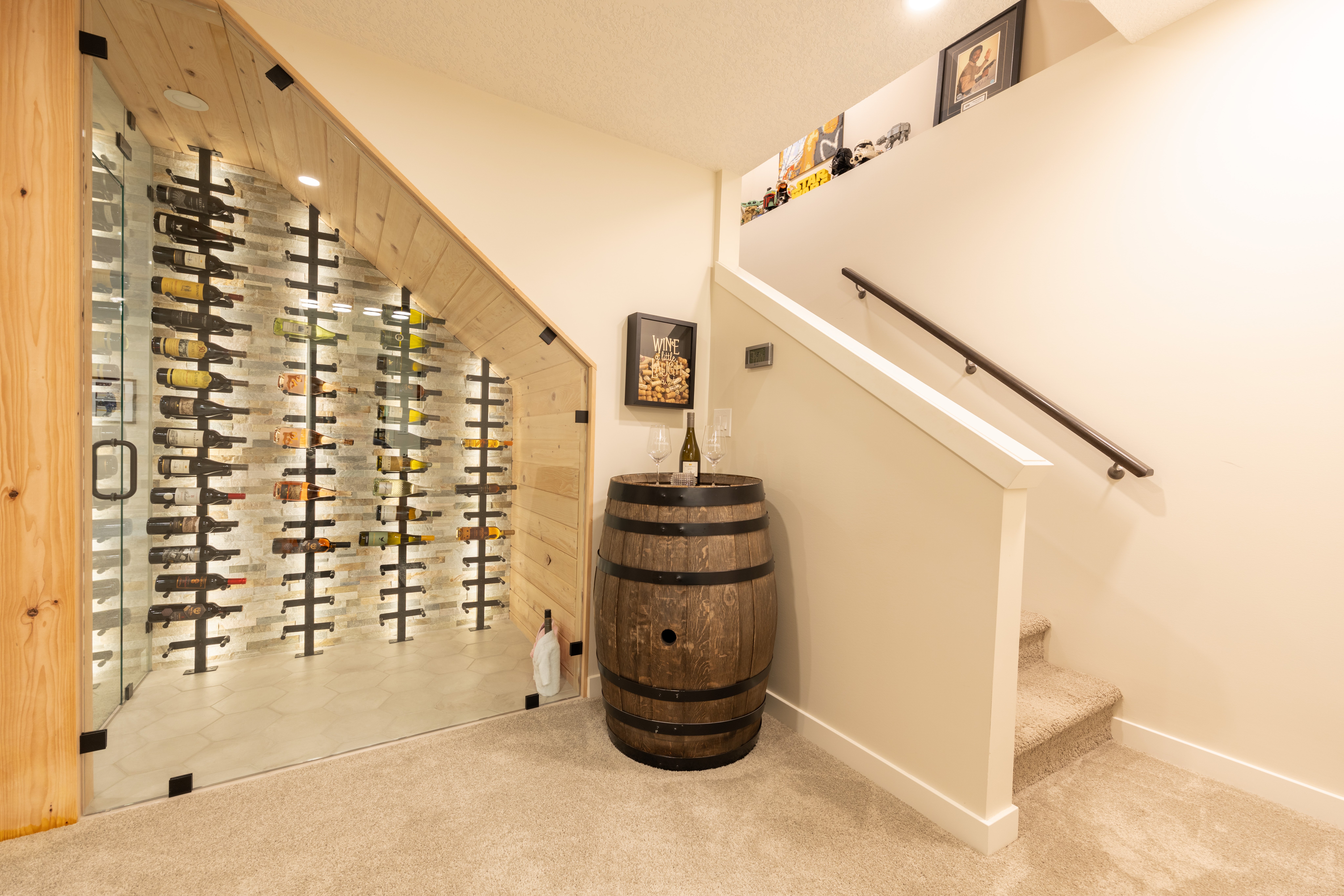 Carpeted steps and a dark handrail rise beside the glass wine enclosure and decorative barrel accent.